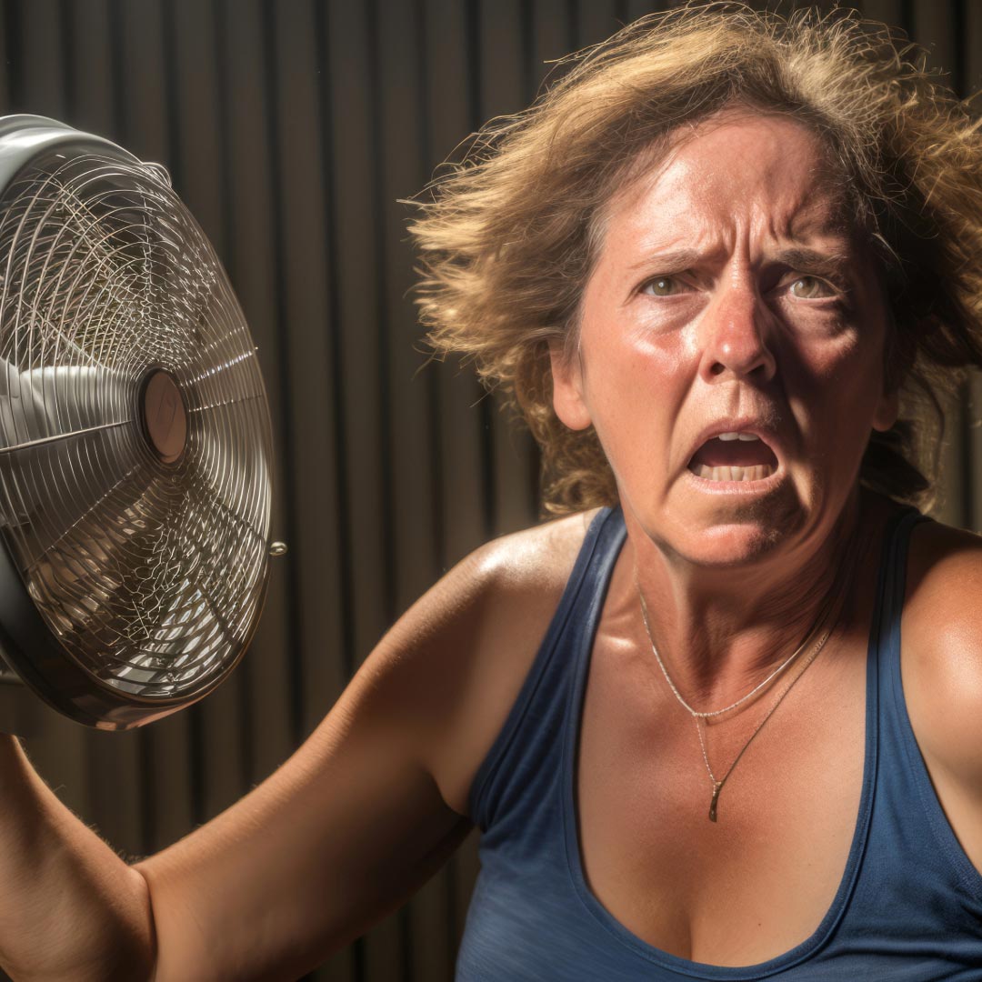 A middle aged sweaty woman with a crazy expression on her face, holding a fan to get some cool air