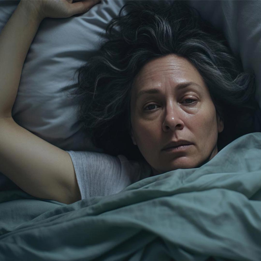 A woman in bed looking extremely tired after a bad night
