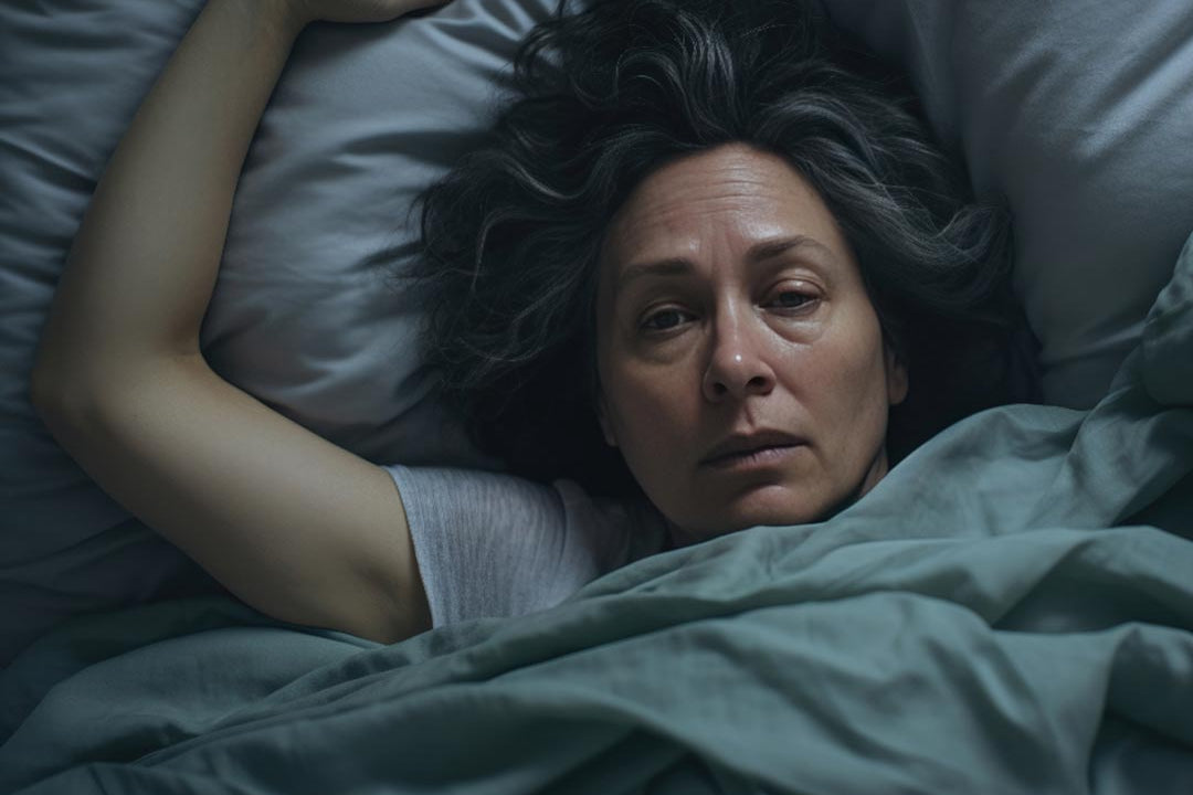 A woman laying in bed looking extremely tired after a night with too little sleep