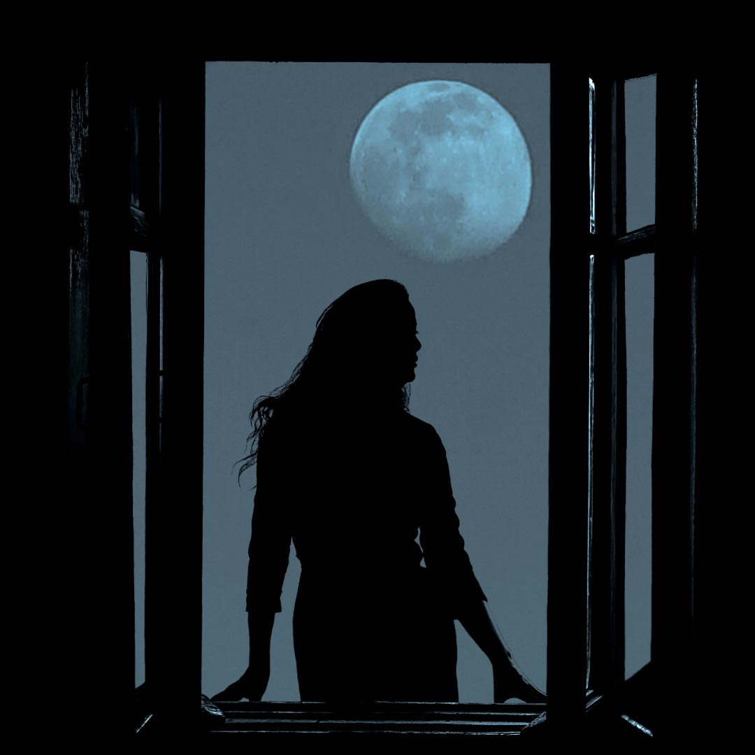 A woman standing in the window at night with the full moon in the background
