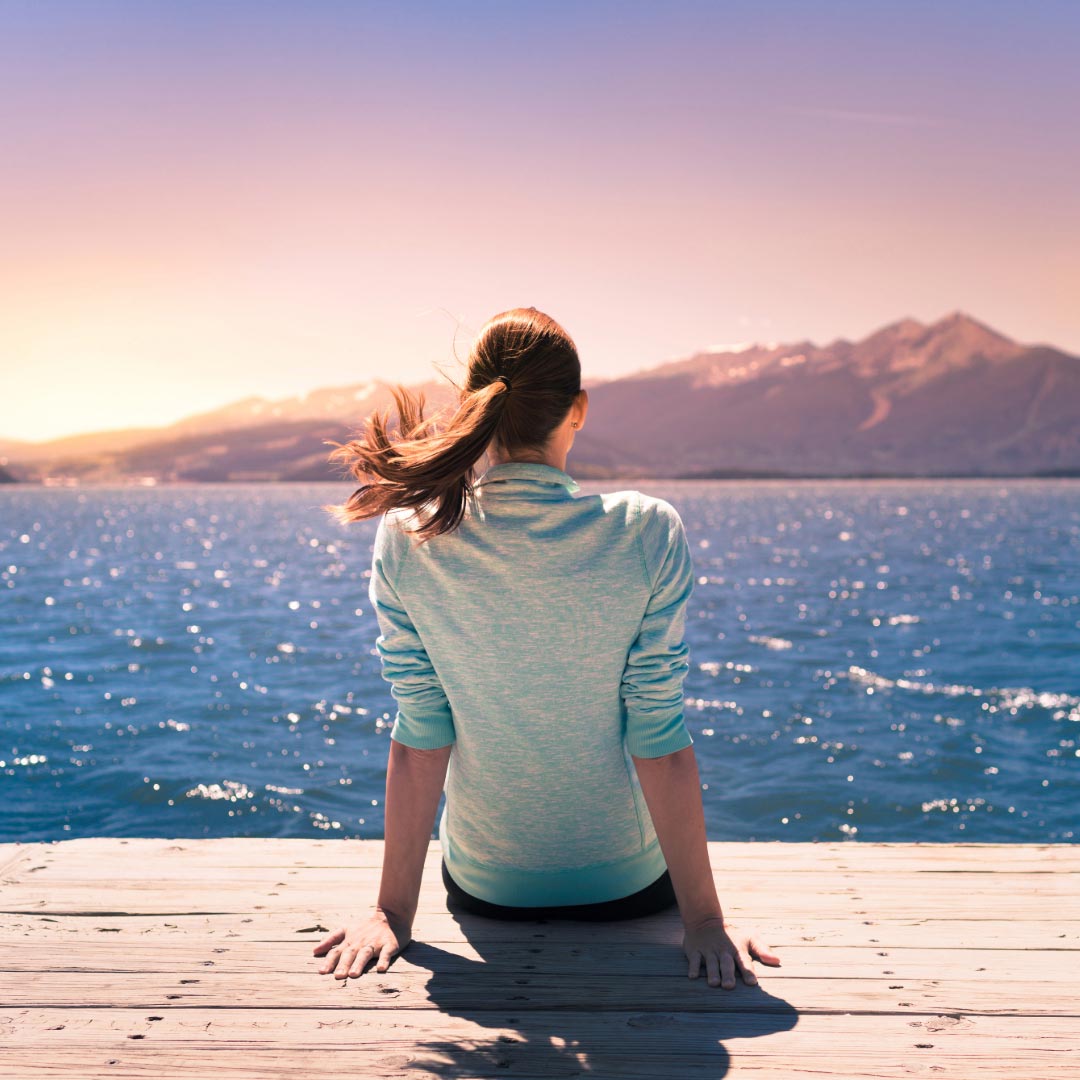 Woman sitting on a dock looking out over the sea