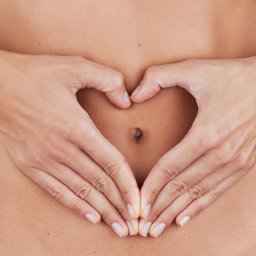 A woman forming her hands as a heart in front of her stomach